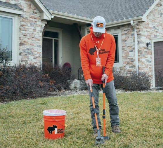 Poo Squad technician performing professional dog waste removal service at a residential home