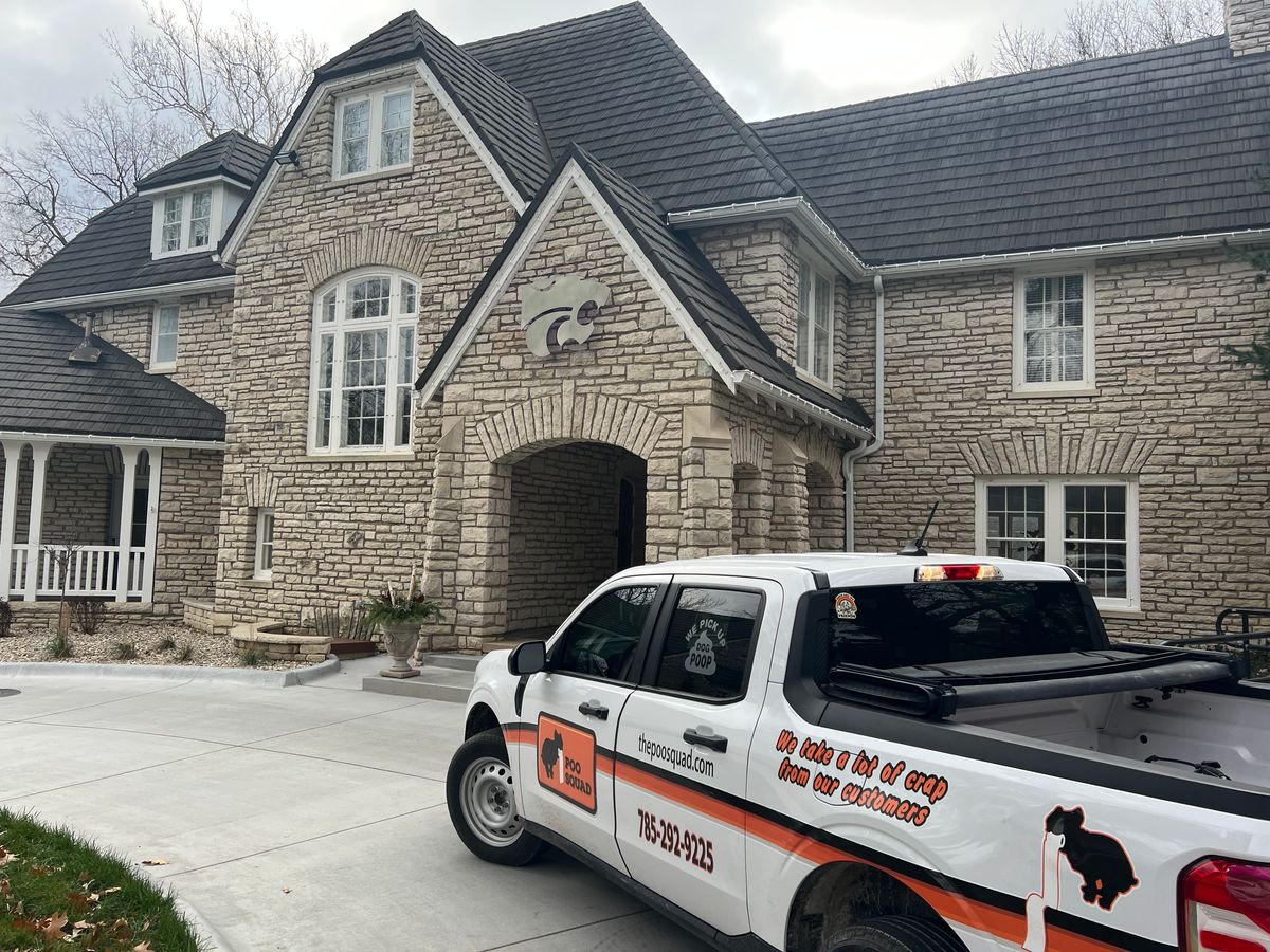 Poo Squad pickup truck parked in the driveway of a large stone house with a K-State Powercat emblem