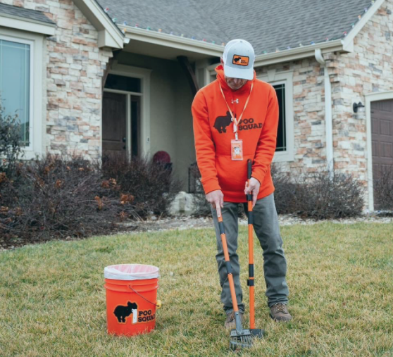 Poo Squad technician performing professional dog waste removal service at a residential home